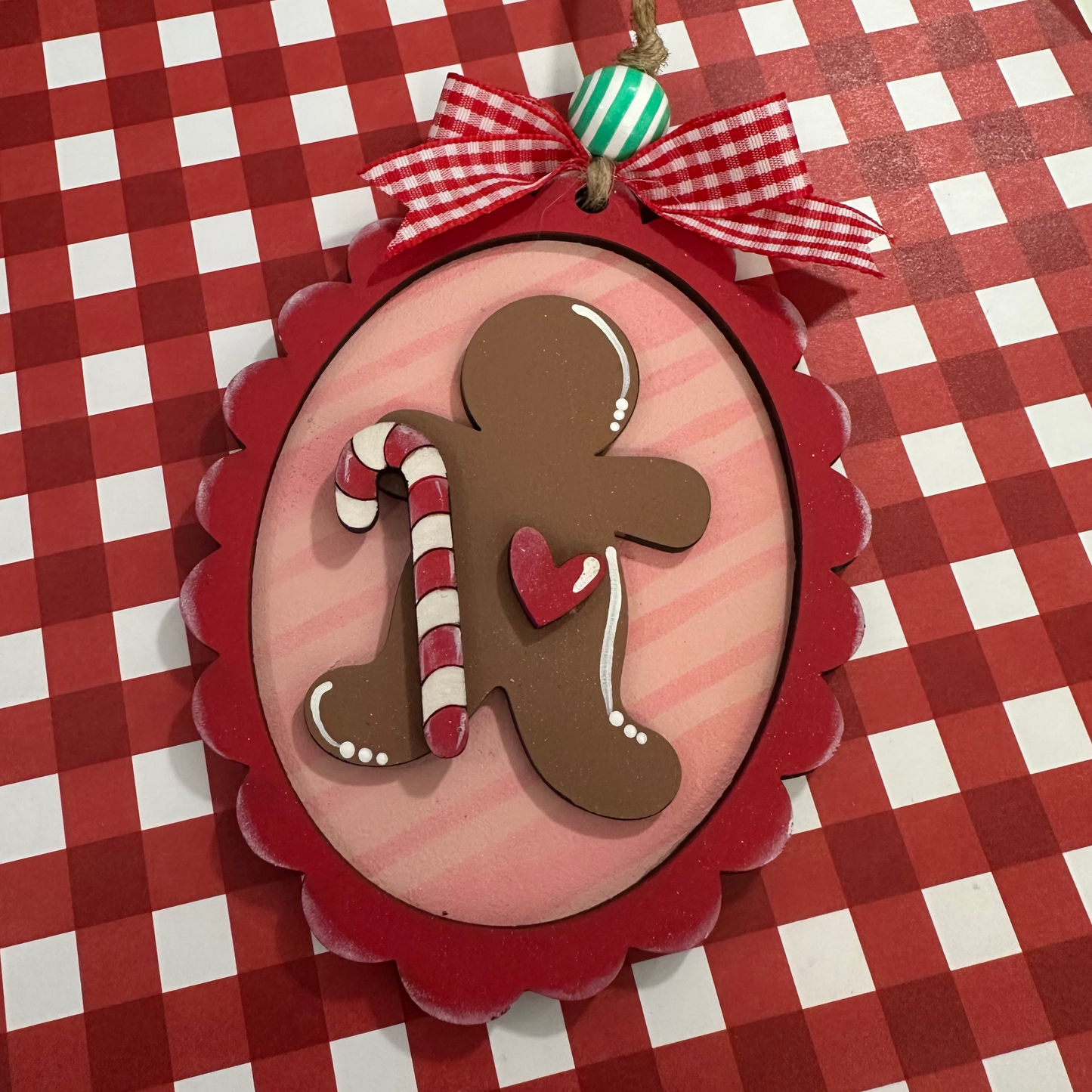Decorative Christmas ornament with gingerbread man and candy cane on a red and white checkered background